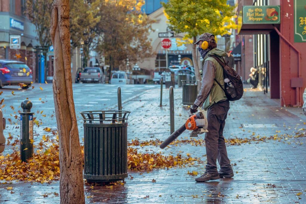 The Man Using Leaf Blowers to Clear The Walk way